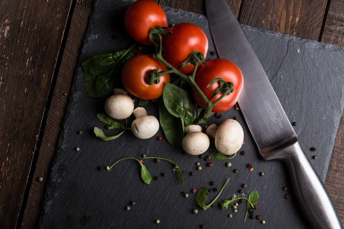 Japans keukenmes met tomaten en champignons op een houten snijplank